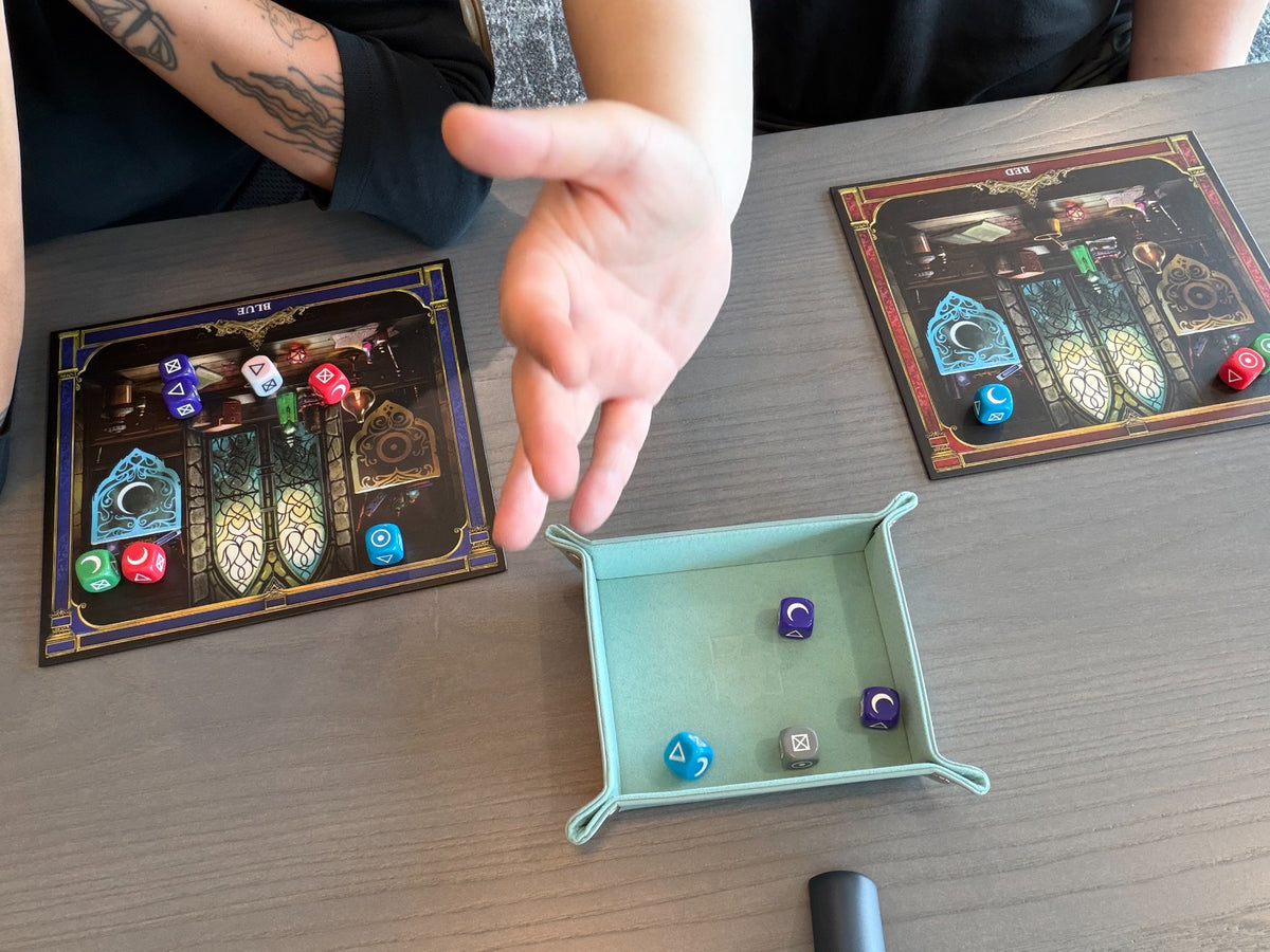Close-up of colorful Alchemy Workshop dice, player mats, and dice tray during gameplay