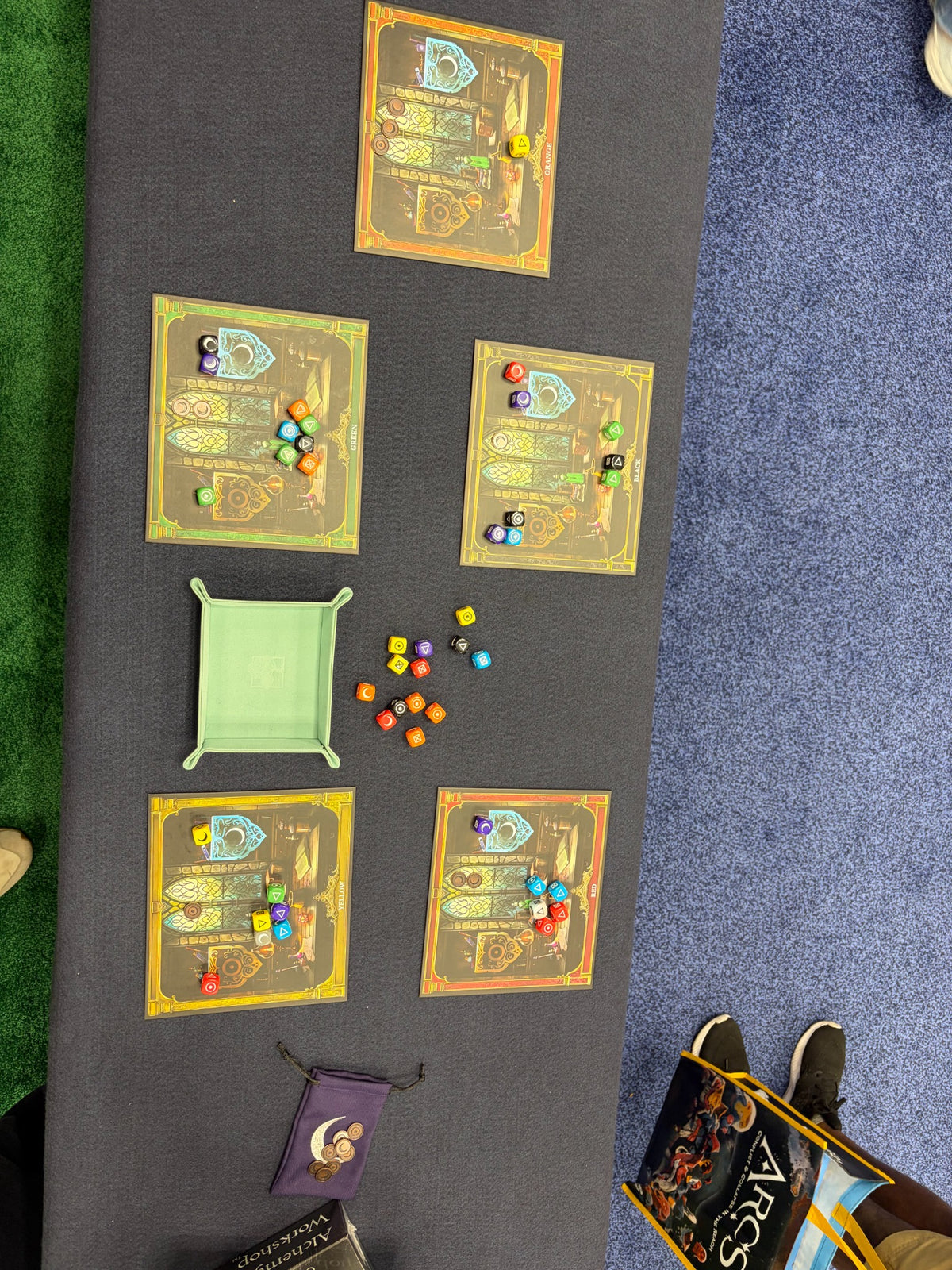 Alchemy Workshop being played on a convention table with colorful dice and player mats