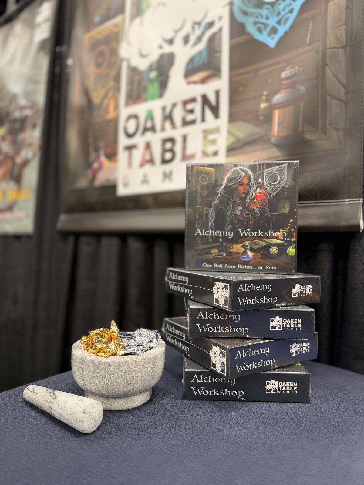 Alchemy Workshop game boxes displayed at the Oaken Table Games booth at Gen Con 2026